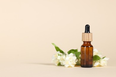 Photo of Essential oil in bottle and beautiful jasmine flowers on beige background, space for text