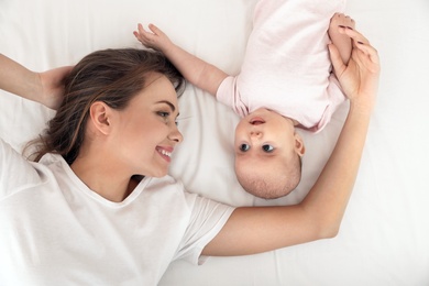 Photo of Portrait of mother with her cute baby lying on bed, top view