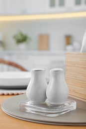 Photo of White ceramic salt and pepper shakers on wooden table, space for text