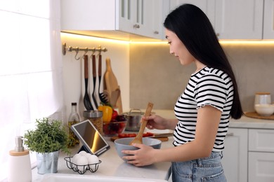 Woman looking at recipe on tablet while cooking in kitchen