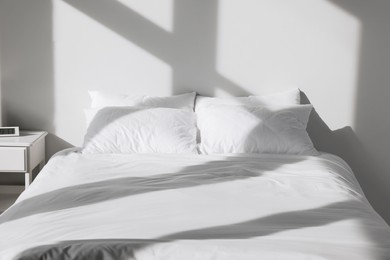 Photo of White soft pillows on bed in room