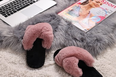 Photo of Soft slippers, magazine and laptop on carpet, closeup