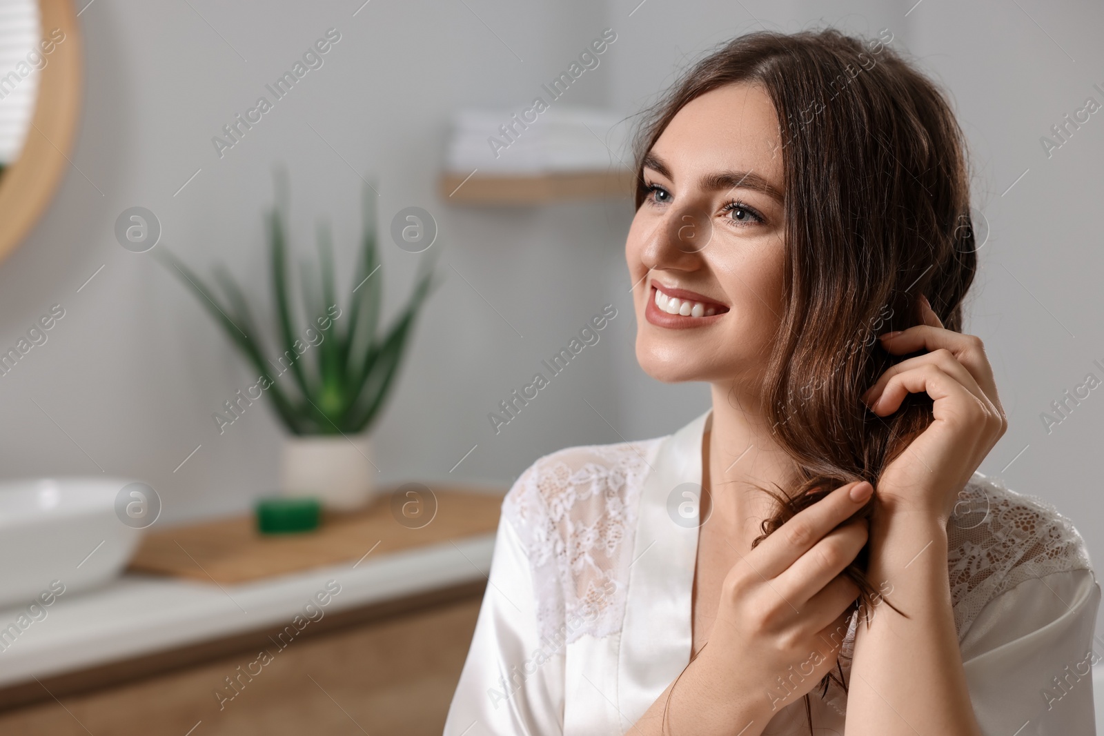 Photo of Young woman applying cosmetic hair mask in bathroom. Space for text