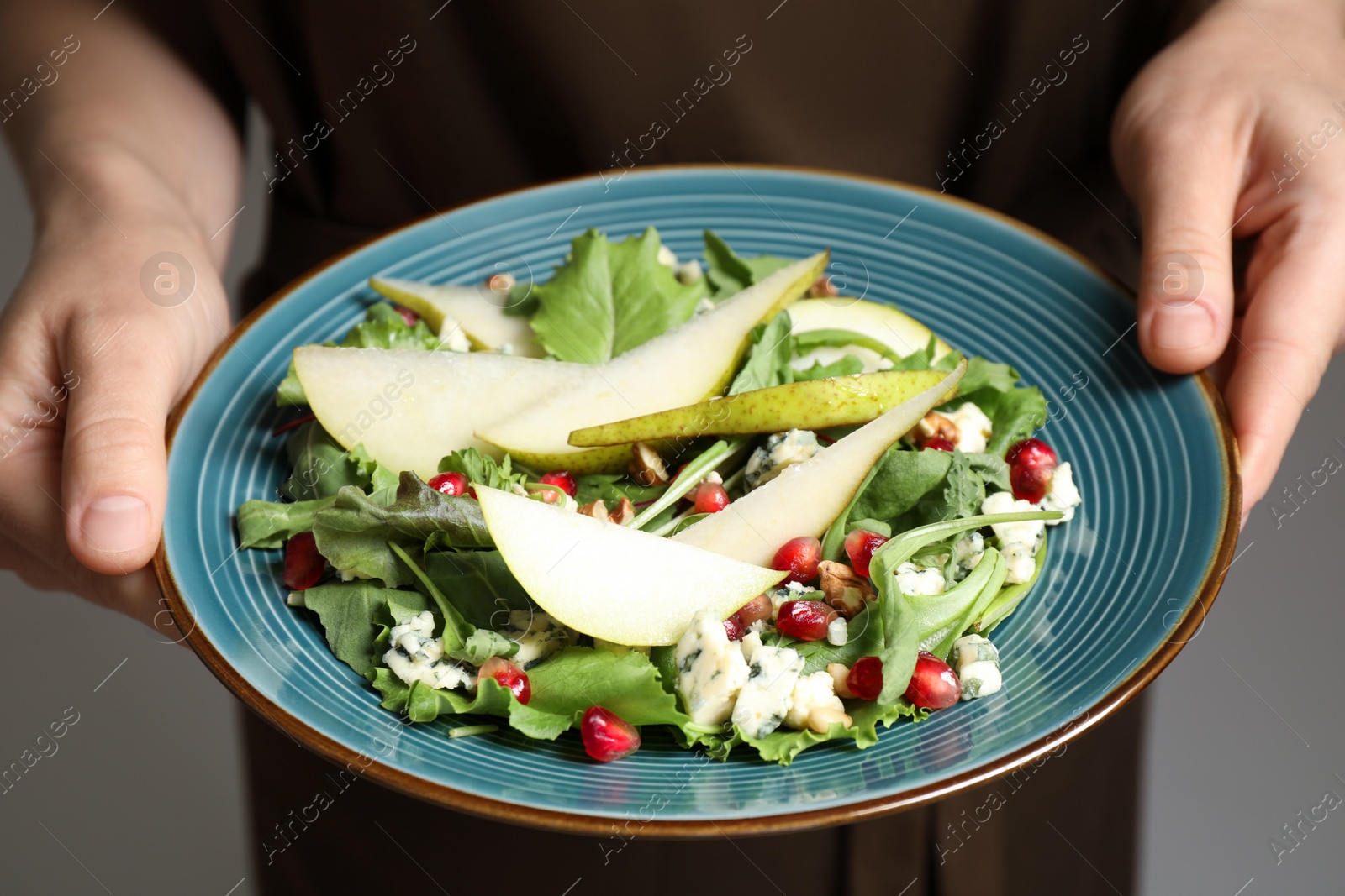 Photo of Woman holding plate with fresh pear salad, closeup
