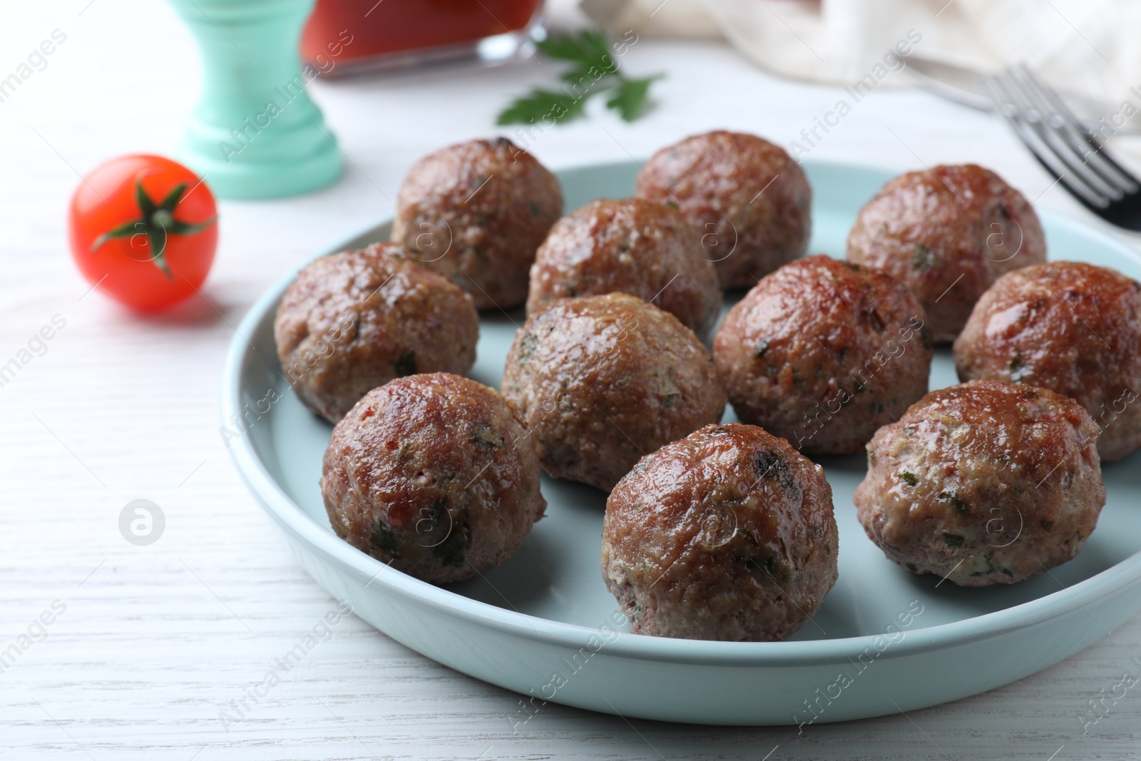 Photo of Tasty cooked meatballs served on white wooden table, closeup