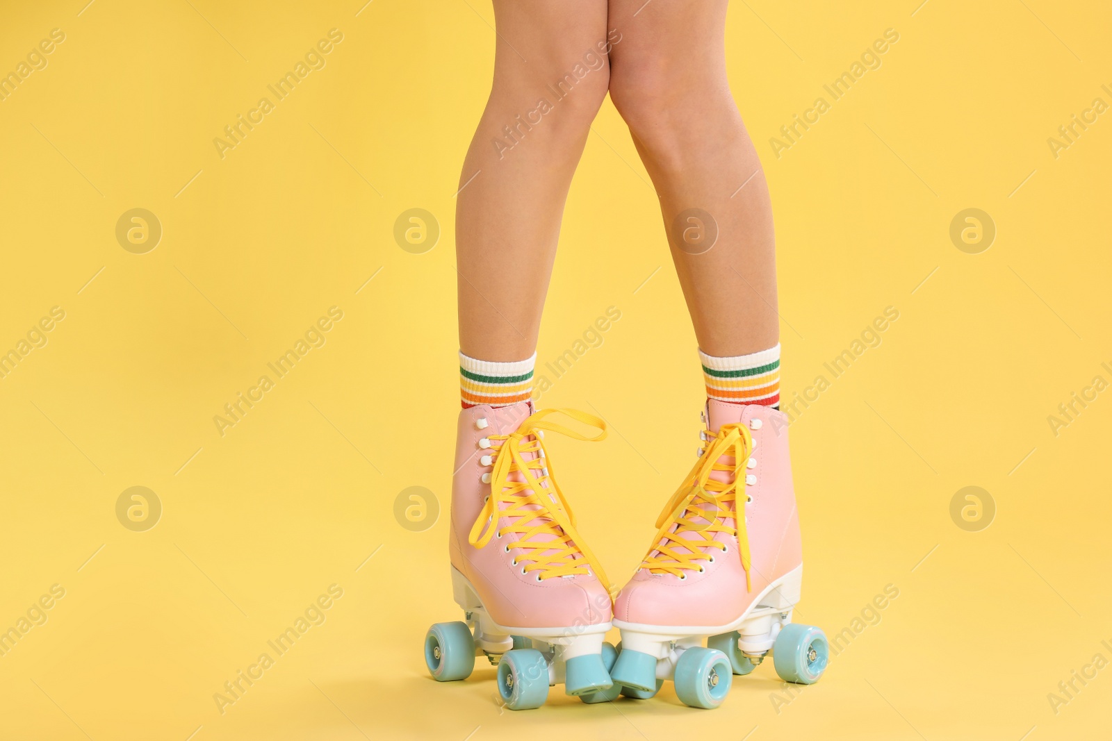 Photo of Young woman with retro roller skates on color background, closeup