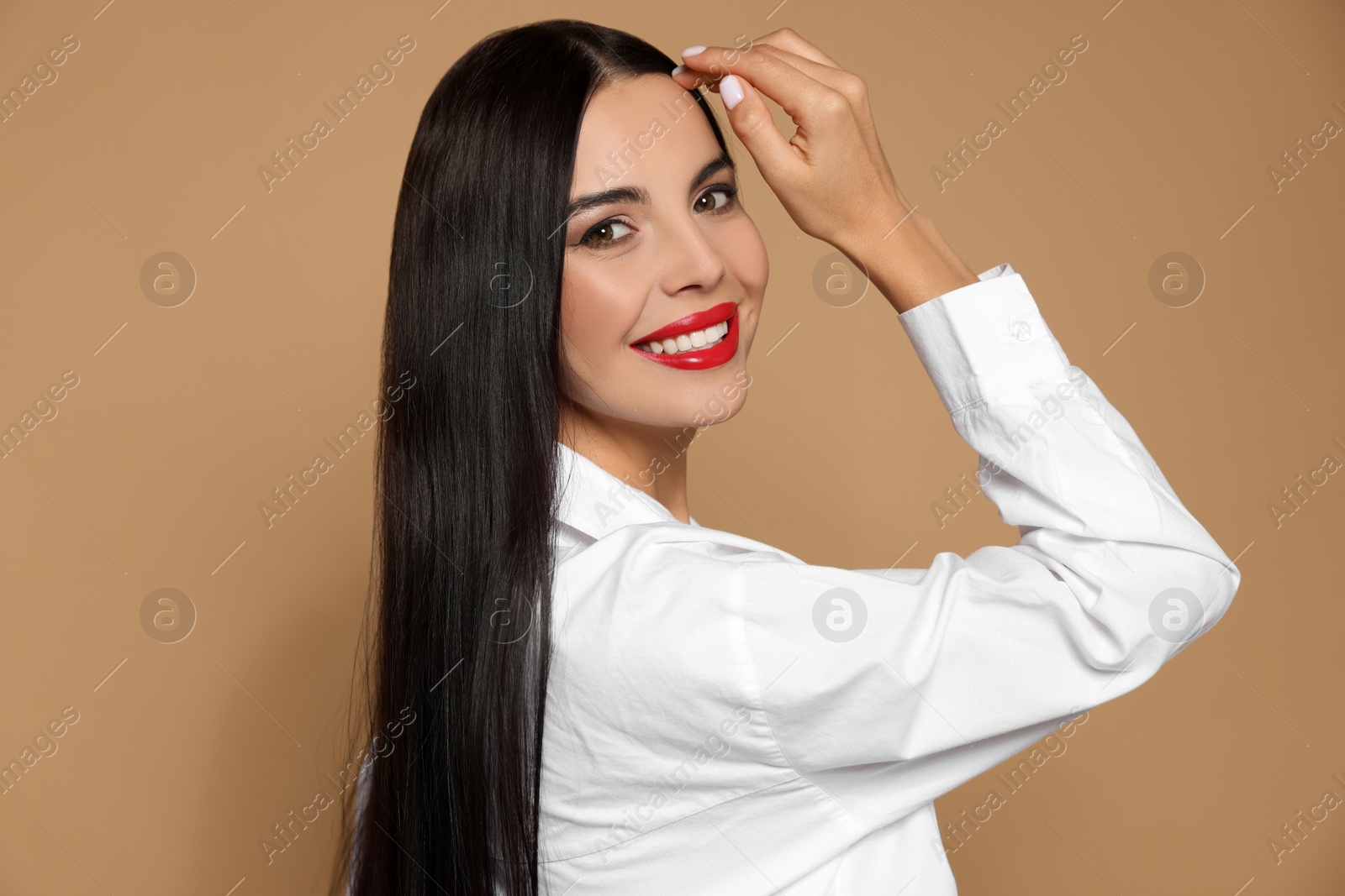 Photo of Portrait of young woman wearing beautiful red lipstick on beige background