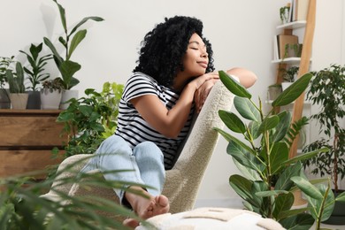 Photo of Woman relaxing in armchair surrounded by beautiful houseplants at home