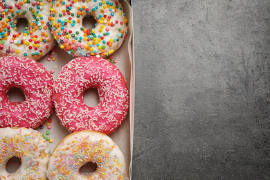 Photo of Delicious glazed donuts on grey table, top view. Space for text