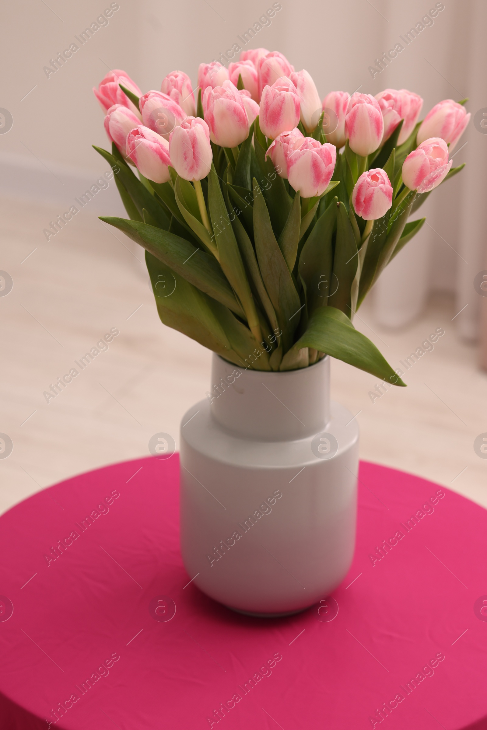 Photo of Beautiful bouquet of fresh pink tulips on table indoors