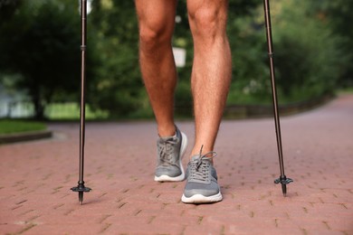 Man practicing Nordic walking with poles outdoors, closeup