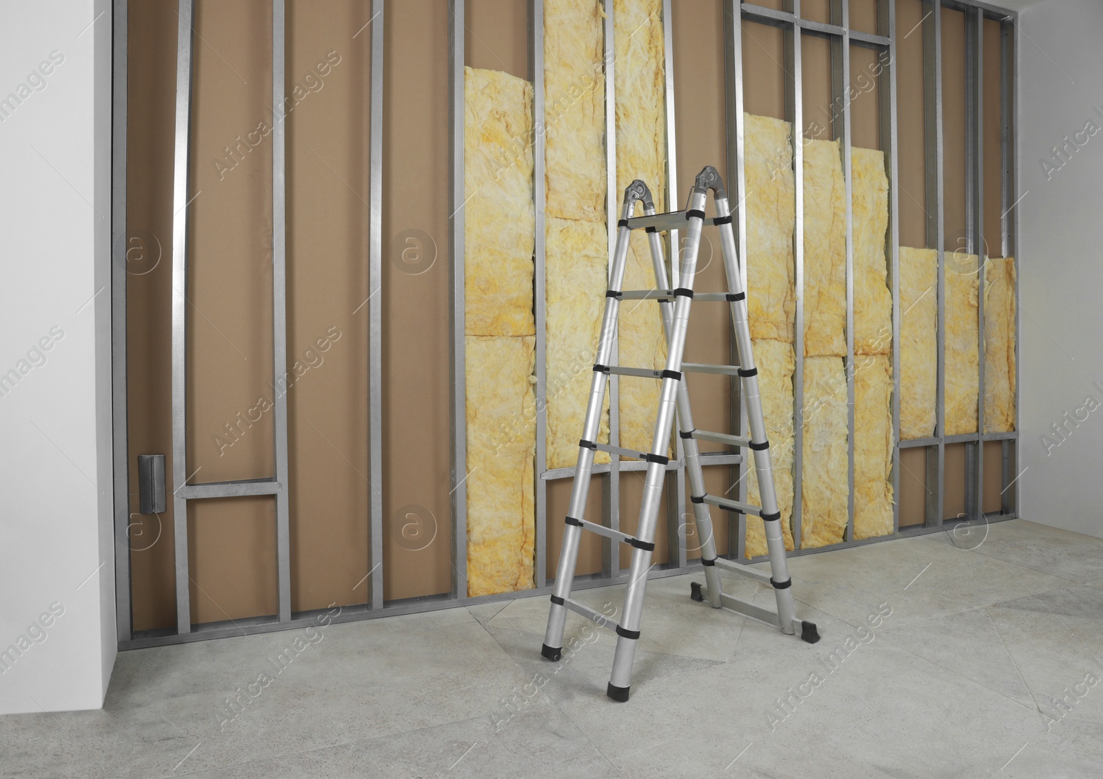 Photo of Ladder near wall with metal studs and insulation material indoors