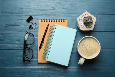 Photo of Flat lay composition with office stationery and cup of coffee on blue wooden table. Space for design