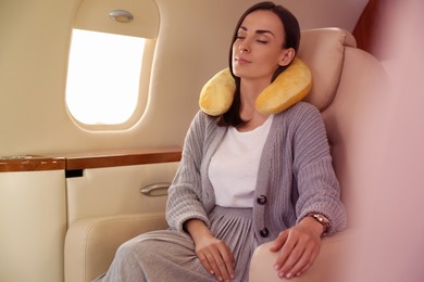 Photo of Young woman with travel pillow sleeping in airplane during flight