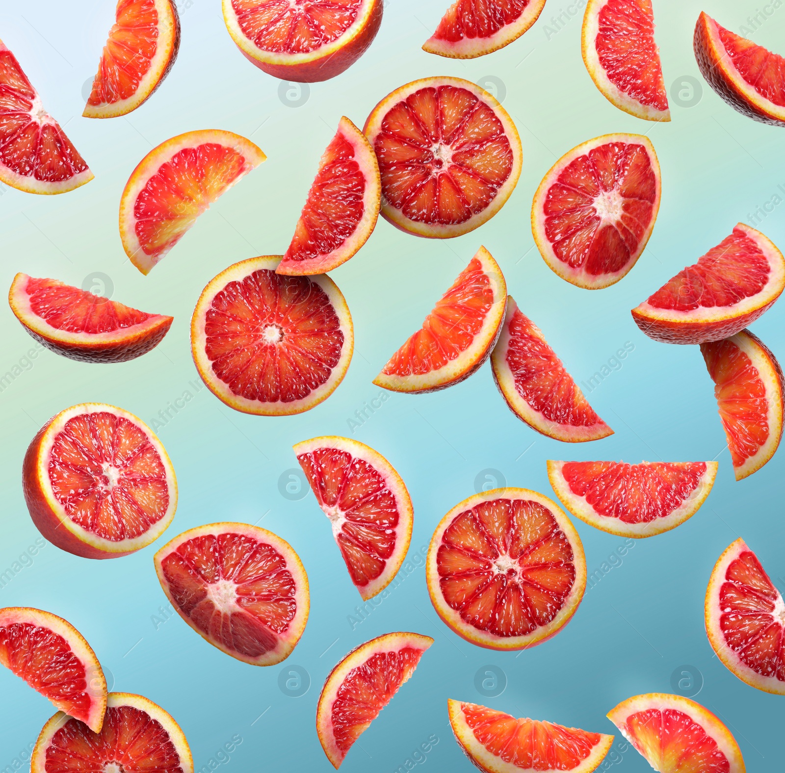 Image of Many cut tasty Sicilian oranges falling on light blue background