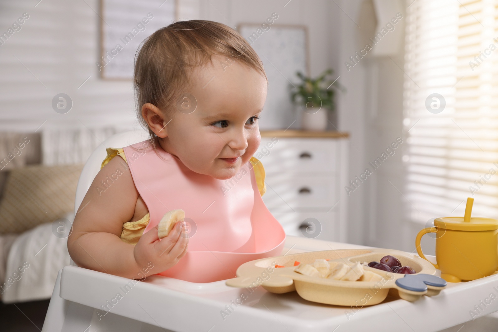 Photo of Cute little baby wearing bib while eating at home