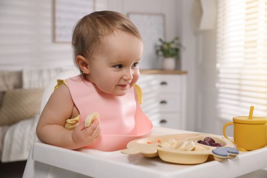 Photo of Cute little baby wearing bib while eating at home