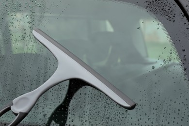 Photo of Wiping car window with drying blade outdoors, closeup