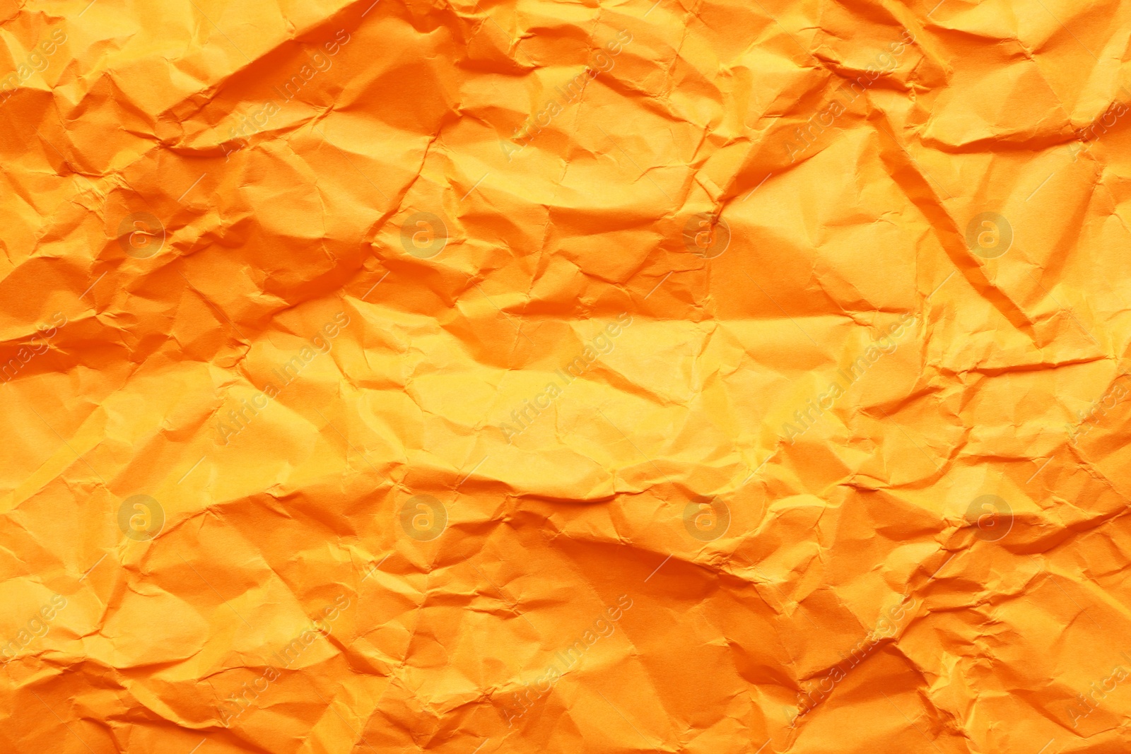 Photo of Texture of orange crumpled paper as background, closeup