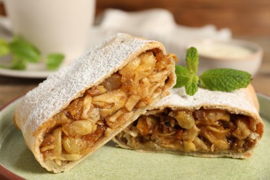 Photo of Delicious strudel with apples, nuts and raisins on plate, closeup