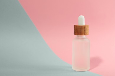 Photo of Bottle of face serum on color background, closeup. Space for text