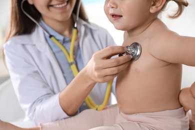 Pediatrician examining baby with stethoscope in clinic, closeup