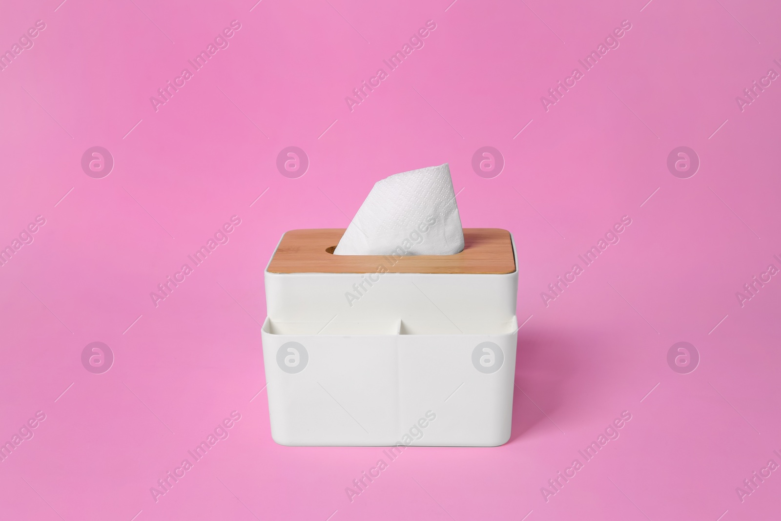 Photo of Holder with paper tissues on pink background