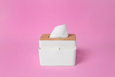 Photo of Holder with paper tissues on pink background