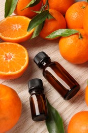 Photo of Bottles of tangerine essential oil and fresh fruits on wooden table, above view