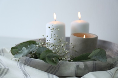 Beautiful eucalyptus branches, flowers and burning candles on fabric, closeup. Interior element