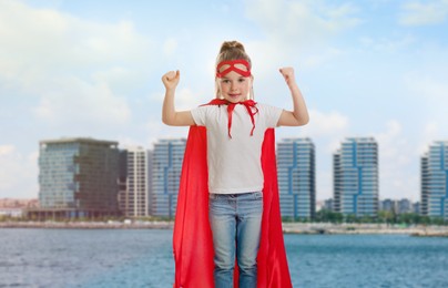 Image of Superhero, motivation and power. Cute girl with mask in cape against city