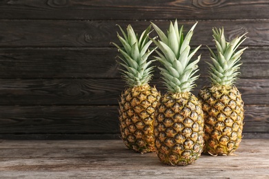 Photo of Fresh pineapples on table against wooden wall