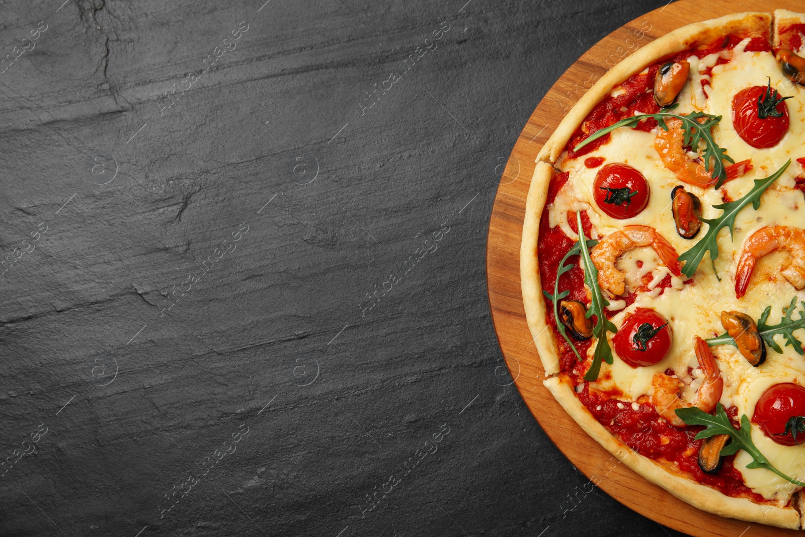 Photo of Delicious seafood pizza on black table, top view. Space for text