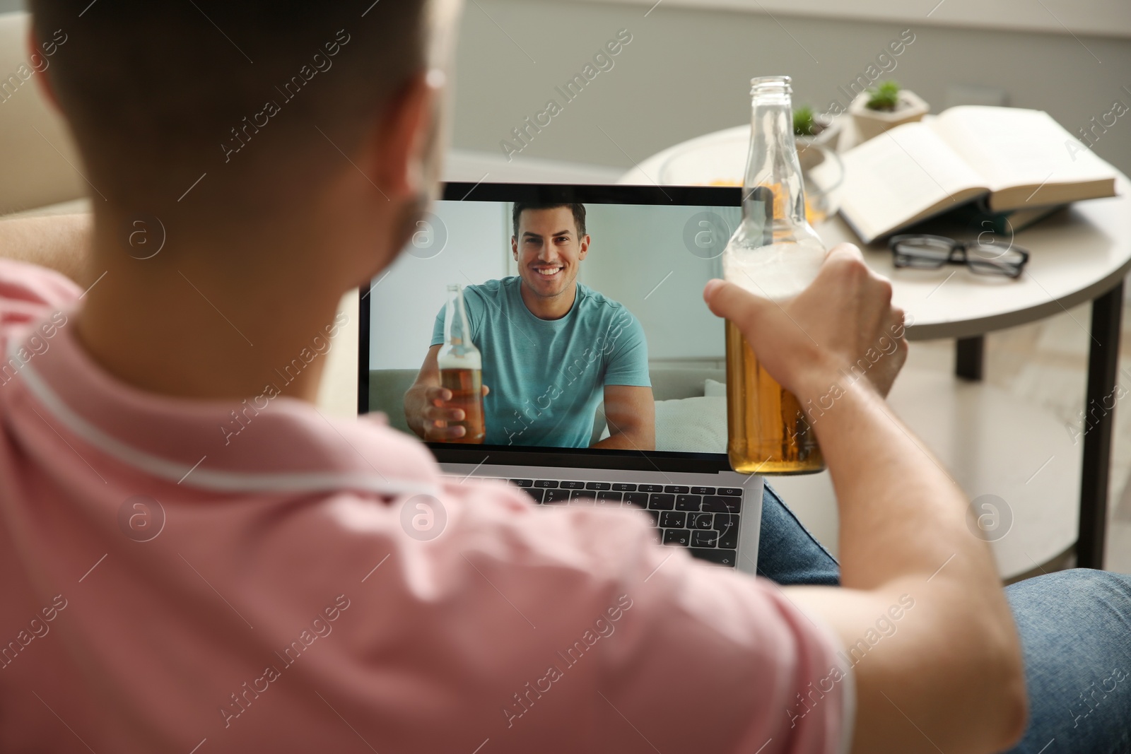 Photo of Friends drinking beer while communicating through online video conference at home. Social distancing during coronavirus pandemic