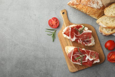 Photo of Tasty sandwiches with cured ham on grey table, flat lay. Space for text