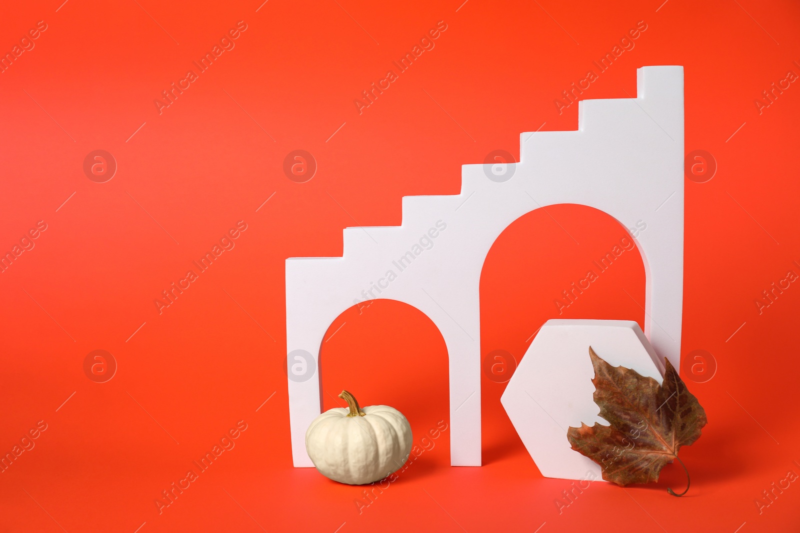 Photo of Autumn presentation for product. White geometric figures, pumpkin and dry leaf on dark orange background