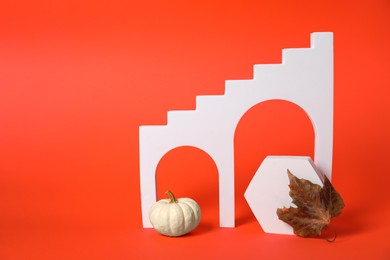 Autumn presentation for product. White geometric figures, pumpkin and dry leaf on dark orange background