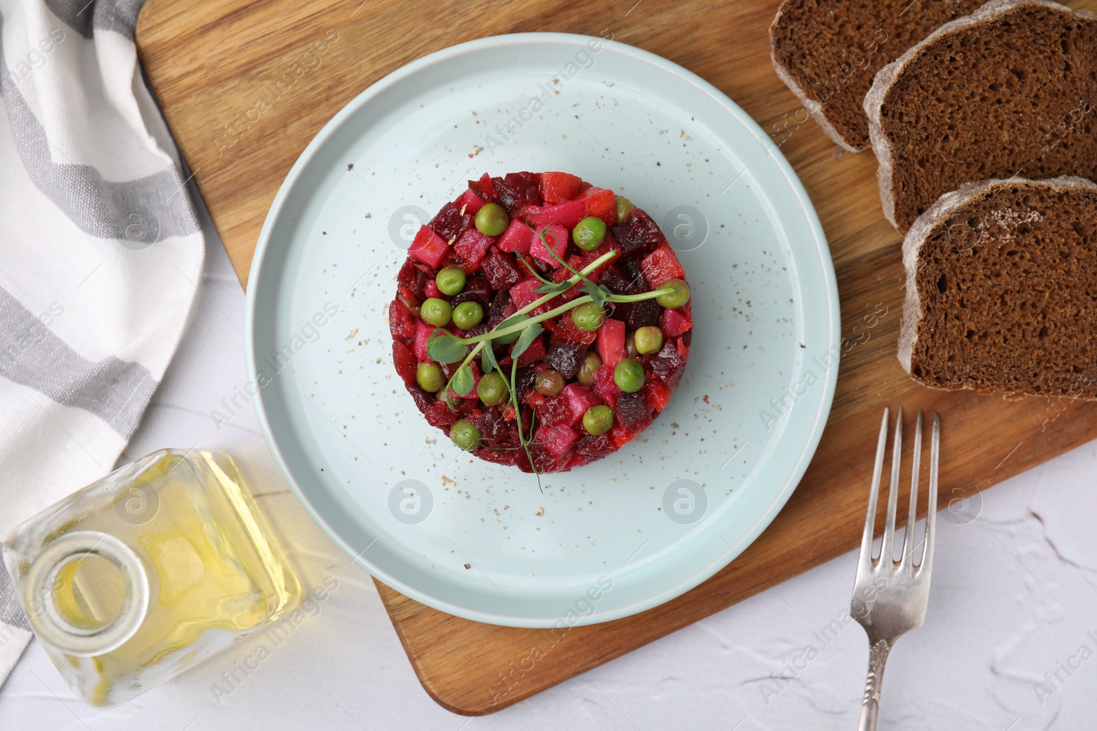 Photo of Delicious vinaigrette salad and slices of bread on white textured table, flat lay