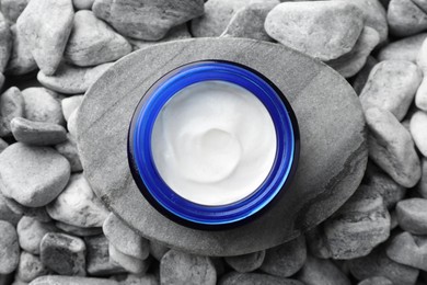 Photo of Jar of moisturizing cream on stones, top view