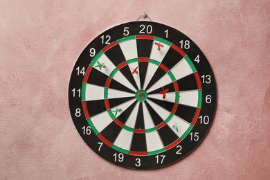 Photo of Arrows hitting dart board on pink wall