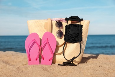 Photo of Summer bag with beach accessories on sand near sea