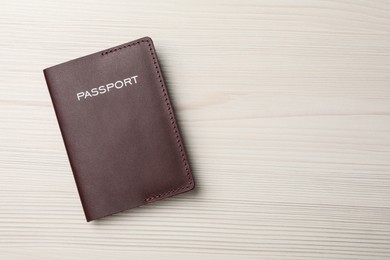 Photo of Passport in brown leather case on white wooden table, top view. Space for text
