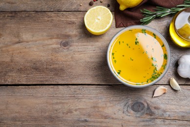 Photo of Bowl of lemon sauce and ingredients on wooden table, flat lay with space for text. Delicious salad dressing