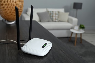 Photo of Wi-Fi router on black wooden table in room. Space for text