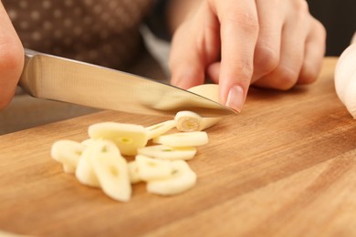 Photo of Woman cutting fresh garlic at table, selective focus
