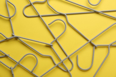 Photo of Empty hangers on yellow background, top view