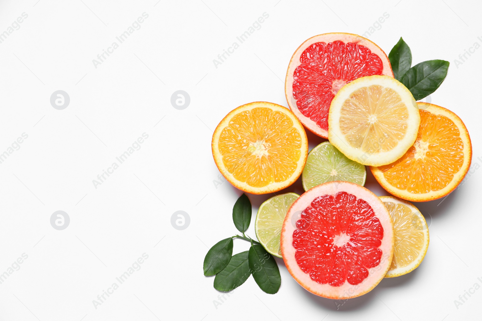 Photo of Different cut citrus fruits and leaves on white table, flat lay. Space for text