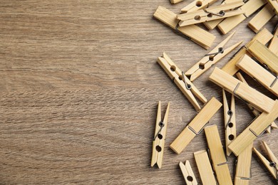 Pile of clothes pins on wooden table, flat lay. Space for text