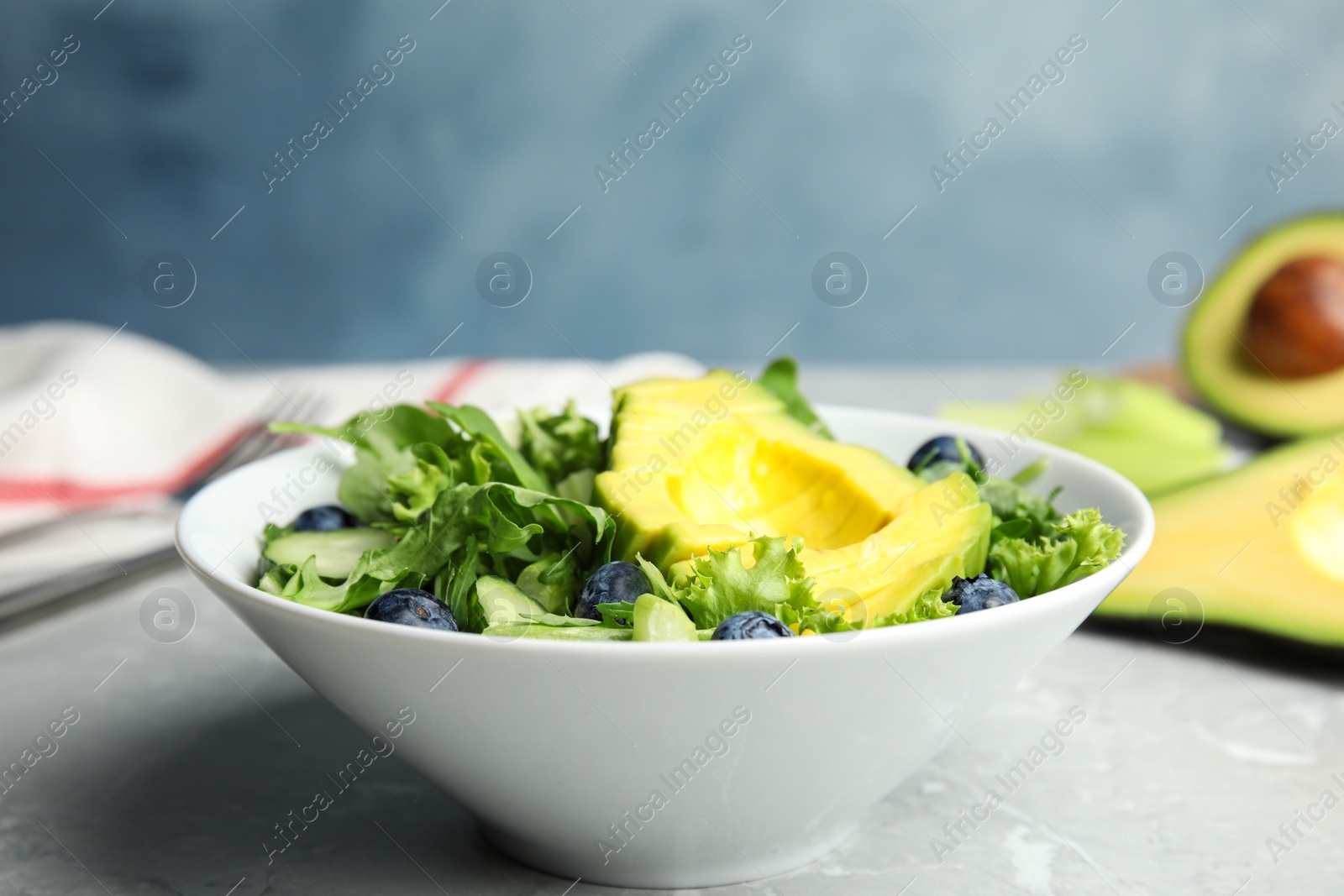 Photo of Delicious avocado salad with blueberries in bowl on grey marble table