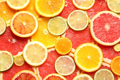 Photo of Slices of fresh citrus fruits as background, top view